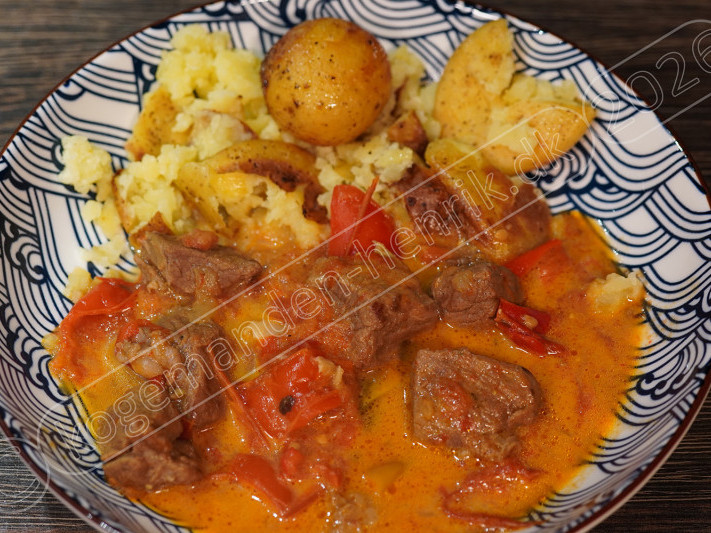 Kogemandens paprikagryde med mørt oksekød, rød peberfrugt og cremet sauce serveret med gyldne kartofler.
